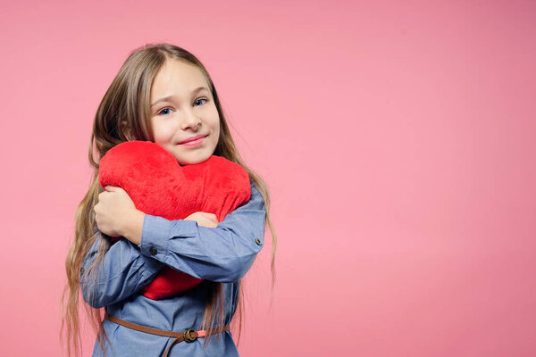Love concept. Cute child girl holding red heart over pink background. Valentine's Day. Mothers Day.