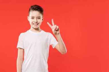 Barış jest kırmızı arka plan üzerinde gösterilen boy gülümseyerek. İki numara. Zafer işareti.