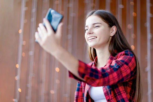 十代の少女は 幸せな写真を撮るために彼女の携帯電話のカメラを見て笑う — ストック写真