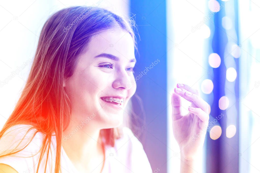 Cheerful laughter of a girl in braces with hand near face.