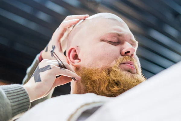 The neck of man's head is being shaved in barbershop.
