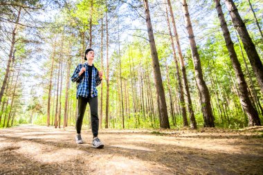 Genç bir adam onun yolculuk yeşil bir orman yoluyla alıyor.