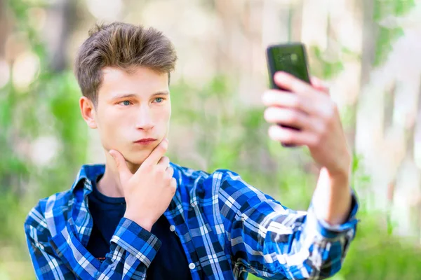 Teenager mit einer Hand am Kinn für ein ernsthaftes Selfie-Porträt. — Stockfoto
