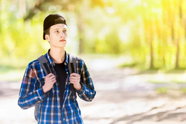 En pojke med en ryggsäck i en skog är tänkande var att gå. — Stockfoto