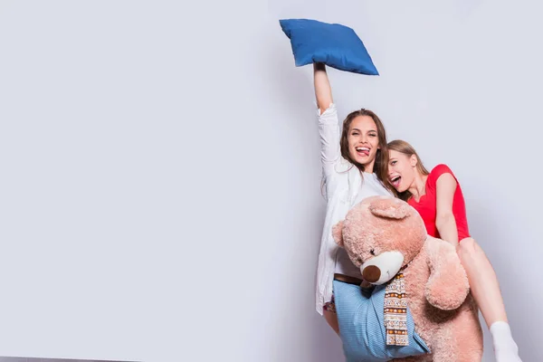 Mooie meisjes met kussens en speelgoed te dragen. — Stockfoto