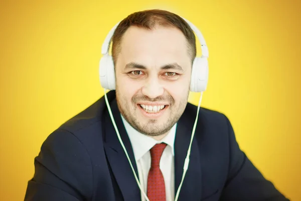 Homem feliz em terno de negócios em fones de ouvido brancos . — Fotografia de Stock