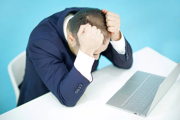 Een zakenman die houdt zijn hoofd kijken naar laptop. — Stockfoto