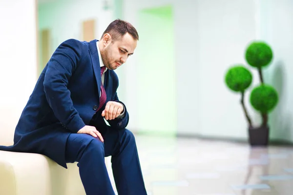 A businessman is thoughtfully sitting in office corridor. — Stock Photo, Image