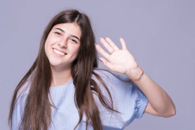 Elini sallayarak kalın kaşları ile gülümseyen kız