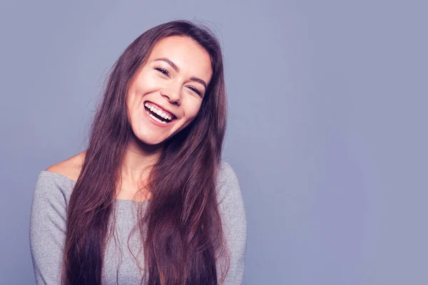 Joven chica positiva con el pelo largo oscuro sobre un fondo azul — Foto de Stock