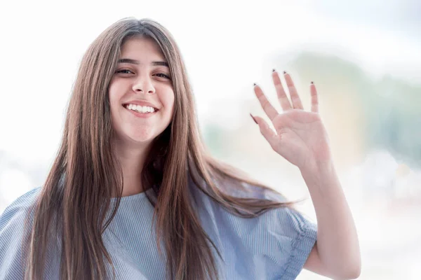 Chica sonriente con cejas gruesas agitando su mano — Foto de Stock