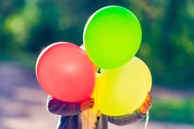 Çocuk üç balon saklanıyor. Doğa arka plan üzerinde