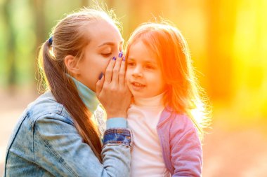 Genç anne onun kulağına fısıldıyor kızı. Yaz ormanda yürümek.