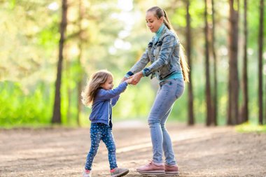 Anne ve kızı ormanda eğleniyorlar. Yaz güneşli gün. Oynak ruh hali 