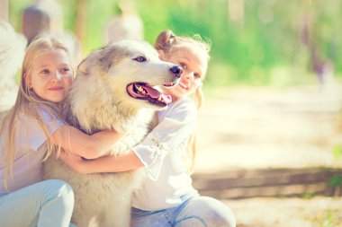 2 mutlu kız yaz ormanda bir köpek sarılma. 