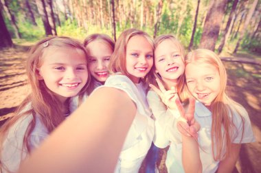 Beş kız çocuklar bir grup yaz ormandaki ağaçlar arka plan üzerinde selfie olun. Parlak güneşli bir günde. Kız.