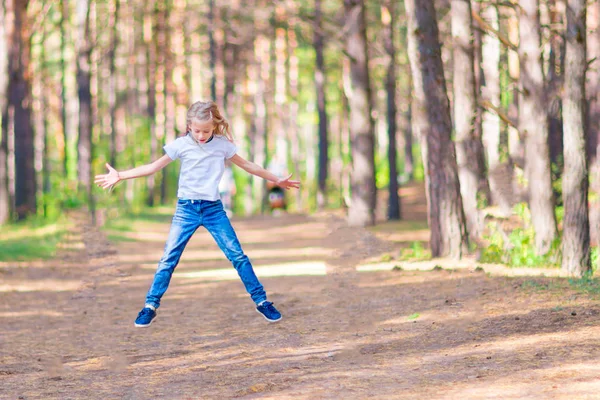 小さな女の子が森で屋外にジャンプします 木の背景に — ストック写真