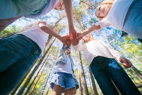 A group of girls kids walking in the summer forest put their hands together. The concept of friendship and unity. Team spirit.