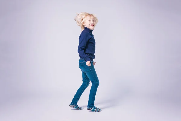 Glædelig langhåret blond lille dreng i fuld vækst i studiet - Stock-foto