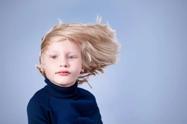 Blond liten gutt med flygende hår på lys bakgrunn i s – stockfoto