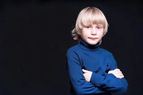 Långhårig blond liten pojke med armar korsade står i th — Stockfoto