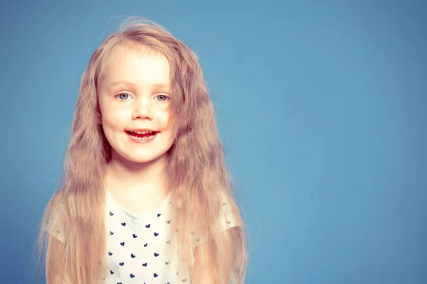 Ritratto di una bambina sorridente con lunghi capelli biondi. Su un blu — Foto Stock