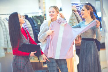 Alışveriş. Mutlu kız bir butik giysilerle üzerinde çalışırken grubu