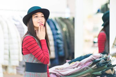 Alışveriş güzel gülümseyen kız bir butikte bir şapka üzerinde çalışıyor