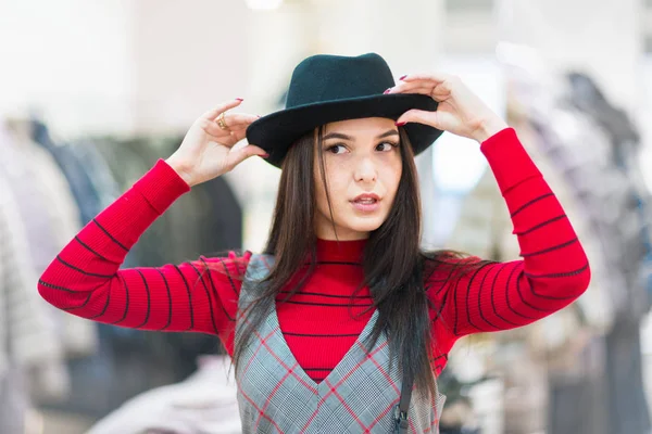 Compras. Hermosa chica probándose un sombrero en una boutique — Foto de Stock