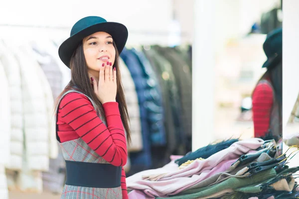 Compras Hermosa chica sonriente probándose un sombrero en una boutique — Foto de Stock