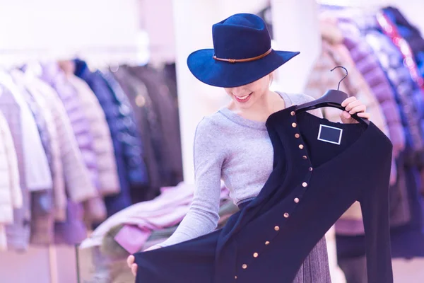 Shopping. Beautiful happy girl in a boutique. Trying on a dress — Stock Photo, Image