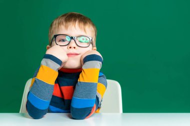 Gözlüklü sıkılmış bir oğlan masada oturuyor. Yakın çekim