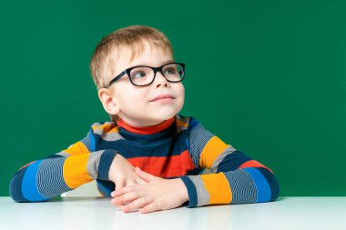 Gözlüklü güzel bir çocuk masada oturuyor ve uzaklara bakıyor. C