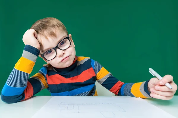 Ein lächelnder Junge mit Brille sitzt an seinem Schreibtisch. Nahaufnahme — Stockfoto