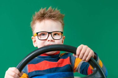 Neşeli çocuk yeşil BAC üzerinde stüdyoda elinde bir tekerlek tutar