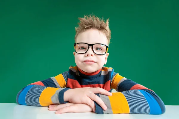 Улыбающийся мальчик в очках. Зеленый фон — стоковое фото