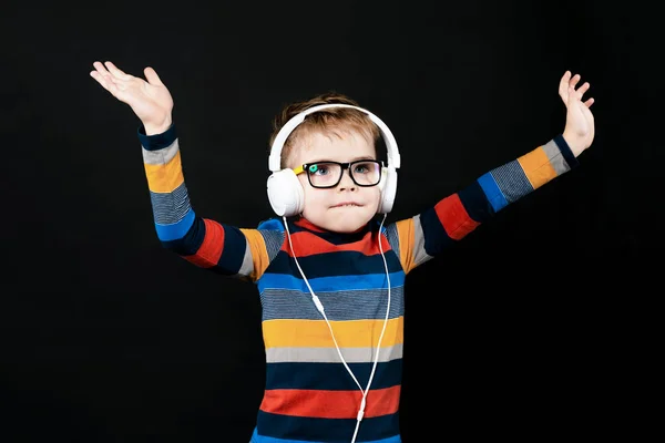 Dancing boy in headphones. On a black background in the studio — Stock Photo, Image