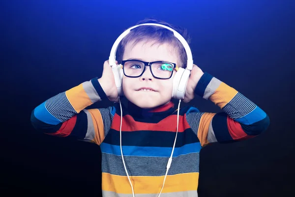 Ein Junge mit Kopfhörern hört Musik. auf schwarzem Hintergrund in t — Stockfoto