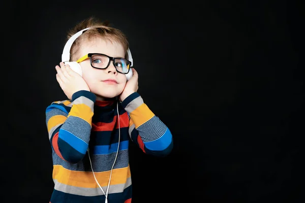 Ένα αγόρι με ακουστικά ακούει μουσική. Σε μαύρο φόντο στο t — Φωτογραφία Αρχείου