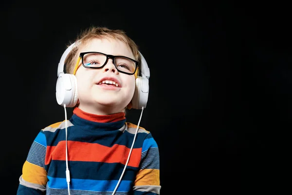 Γέλιο αγόρι με ακουστικά. Σε μαύρο φόντο στο στούντιο. — Φωτογραφία Αρχείου