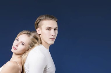 Genç çift sırt sırta Studio koyu mavi ba üzerinde poz