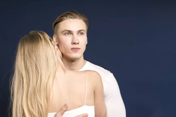 Bonito jovem casal posando em um fundo azul escuro no s — Fotografia de Stock