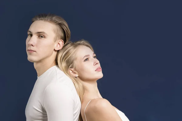 Couple back to back posing in the studio on a dark blue backgrou