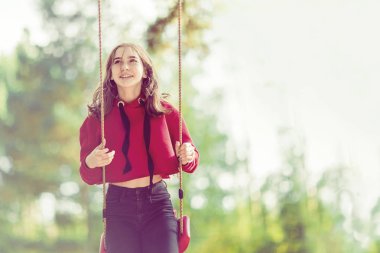 Yaz ormanında bir salıncak üzerinde gülümseyen kız