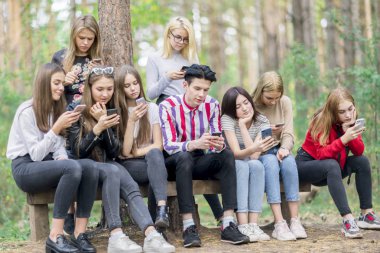 Yaz ormanında telefonları ile Genç arkadaşlar bir b oturuyor
