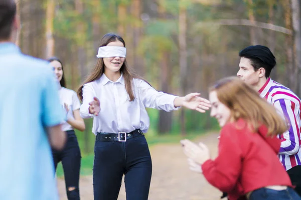 The game of blind man\'s buffoonery. Blindfolded girl. Teenagers in the summer forest