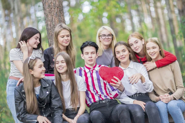 8人の女の子に囲まれた手に赤いハートを持つ男. — ストック写真