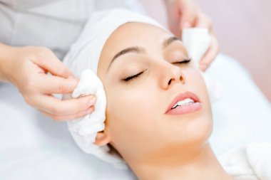 Kozmetolog elleri cildi temizler. Yüz cilt bakımı. Kozmetoloji prosedürü güzel kız. Güzellik Salonu ziyareti