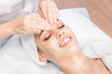 Kozmetoloji. Bir Kozmetolog elleri bir maske ile yüz masajı yapmak. Spa prosedürinde gülümseyen kız. Yüz Bakımı