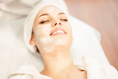 Kozmetoloji. Maske ile prosedür üzerine gülümseyen kız yüz uygulandı. Ziyaret kozmetoloji Kliniği